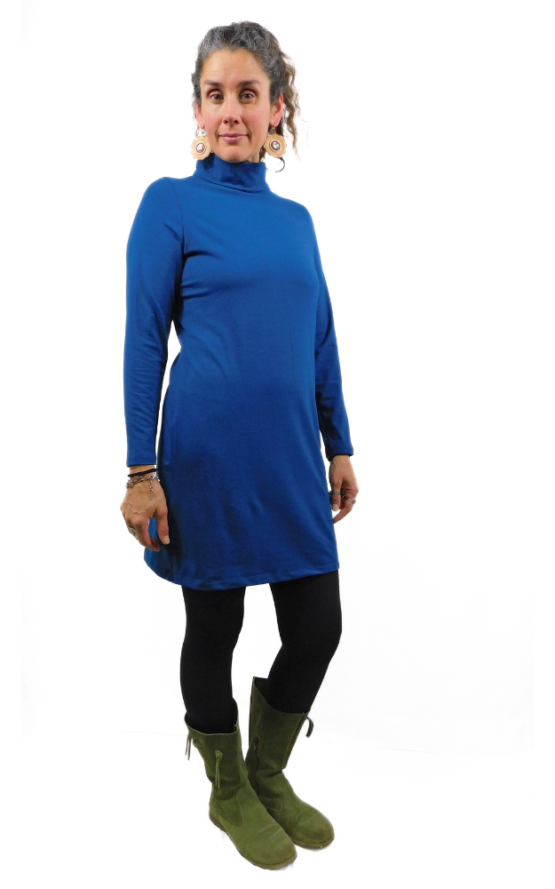 Woman wearing a blue turtleneck bamboo clothing dress with green boots on a white background