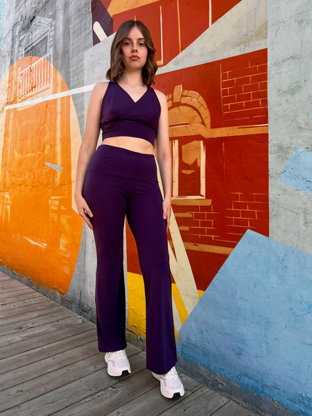 Woman in purple outfit standing in front of a colorful mural wearing bamboo clothing.