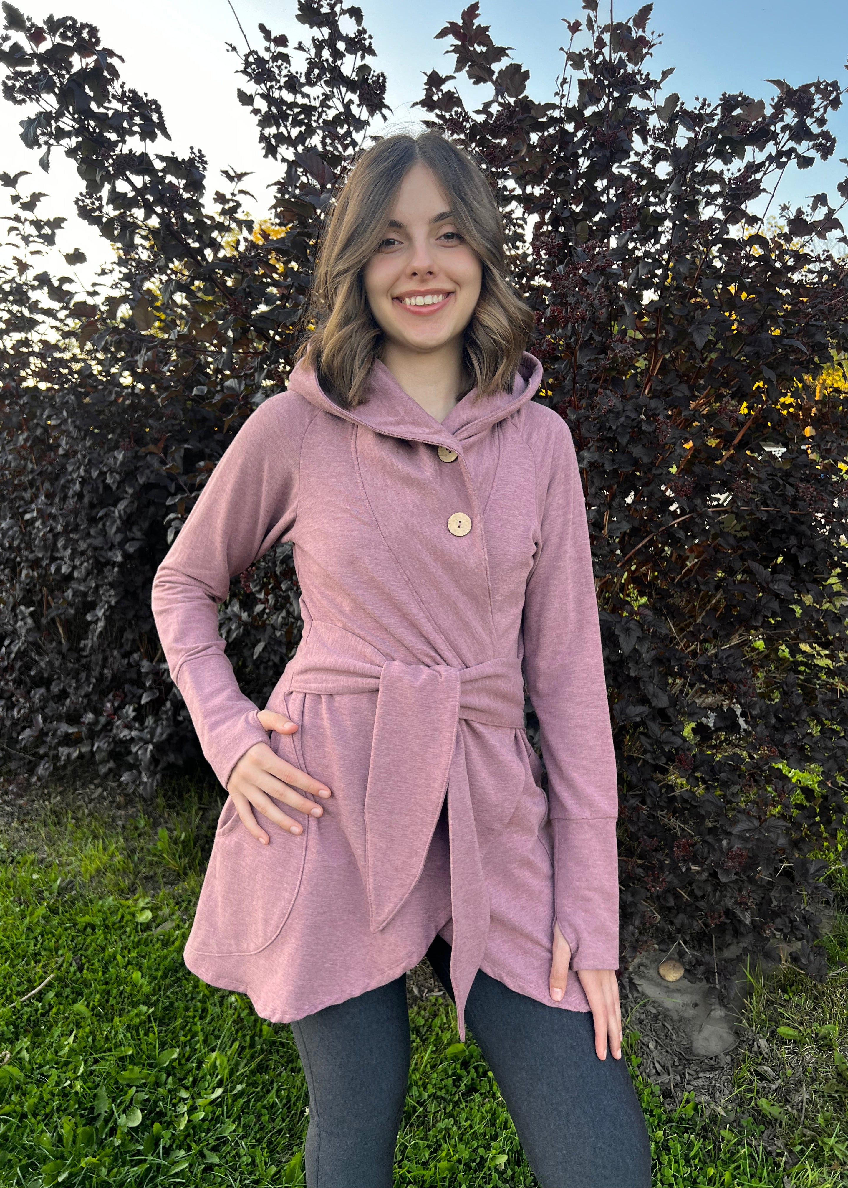 Person wearing a bamboo fleece bamboo clothing pink coat standing outdoors with greenery around